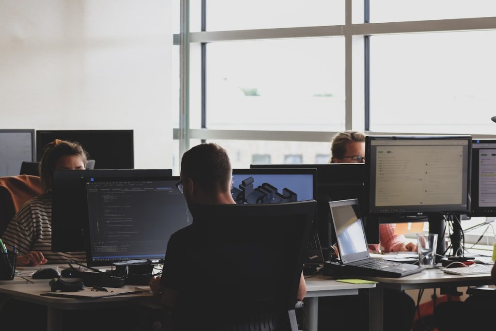Cyber security specialisten aan het werk achter meerdere schermen met code en monitoring dashboards