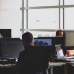 Cyber security specialisten aan het werk achter meerdere schermen met code en monitoring dashboards
